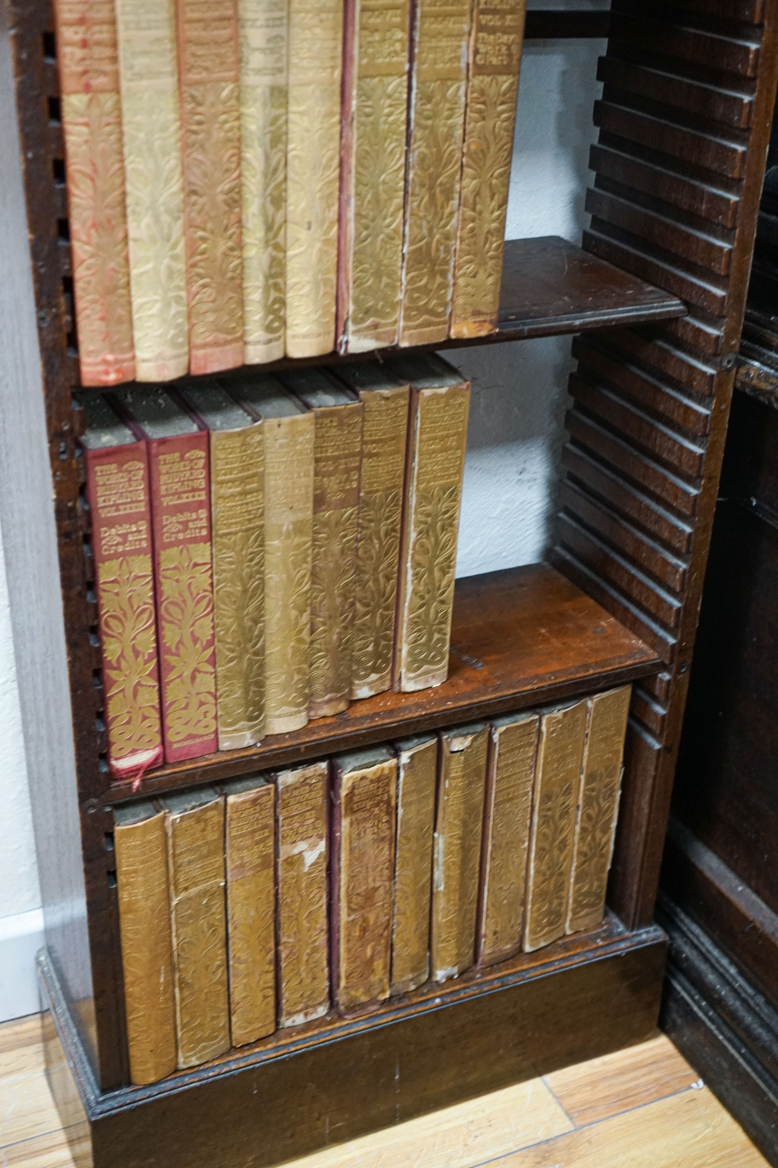 A Georgian mahogany wall-mounted narrow bookshelf, width 48cm, depth 18cm, height 147cm, containing a limited edition Works of Rudyard Kipling in 33 volumes, published 1900